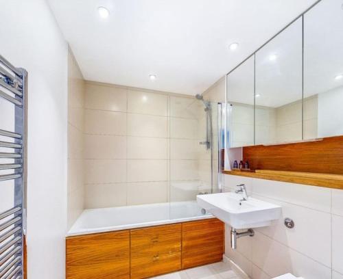 ein Badezimmer mit einem Waschbecken und einer Badewanne in der Unterkunft Heronsgate GH016 in London