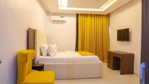 um quarto de hotel com duas camas e uma cadeira amarela em LA FIFTHIN VILLA em Lekki