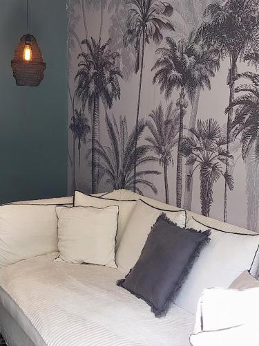 un canapé blanc dans un salon avec du papier peint à motifs de palmiers dans l'établissement VILLA COTE SUD, à Avignon