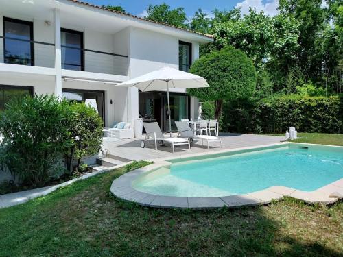 - une piscine avec un parasol en face d'une maison dans l'établissement VILLA COTE SUD, à Avignon