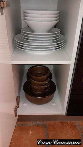 a stack of plates and bowls in a cabinet at Antica torre del castello Casa Ceresiana in Carabietta