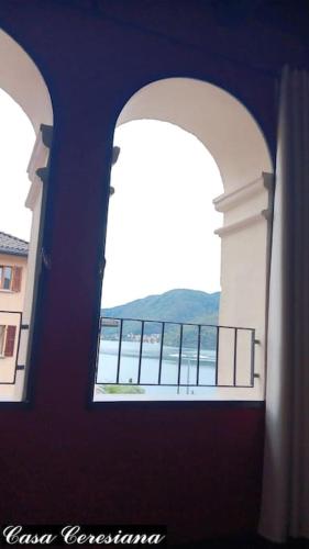 two arched windows in a building with a view of the water at Antica torre del castello Casa Ceresiana in Carabietta