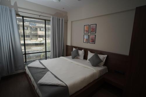 een slaapkamer met een bed en een groot raam bij SUNBRIGHT ROOMS & RESIDENCY in Thane