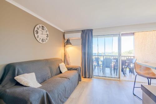 un salon avec un canapé et une horloge au mur dans l'établissement Appartement des Marines - Welkeys, à Cogolin