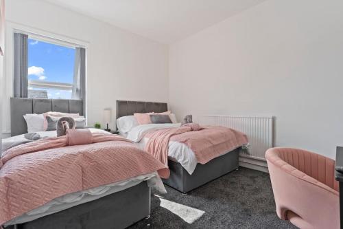 a bedroom with two beds and a chair at Masterson House By RMR Accommodations - NEW - Sleeps 9 - Modern - Parking - Central in Stoke on Trent