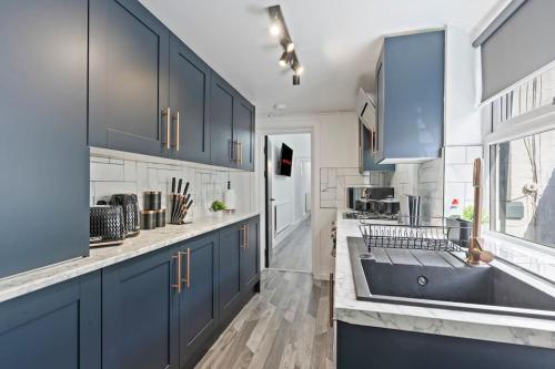 a large kitchen with blue cabinets and a sink at Masterson House By RMR Accommodations - NEW - Sleeps 9 - Modern - Parking - Central in Stoke on Trent