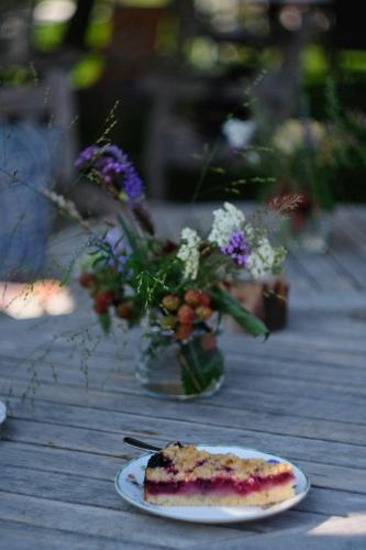 a piece of cake on a plate next to a vase of flowers at In de 7e Hemel in Grashoek