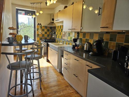 une cuisine avec des placards en bois et des tabourets de bar dans l'établissement La Poserie des Monts et Vallées, à Esson