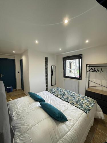 une chambre avec un grand lit blanc avec des oreillers bleus dans l'établissement La Poserie des Monts et Vallées, à Esson