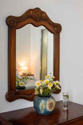 a vase with flowers on a table in front of a mirror at Vallas Apartments & Villas in Firostefani