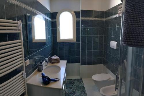 a blue tiled bathroom with a sink and two toilets at Appartamento a Riccione con balconcino vista mare in Riccione