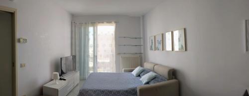 a white bedroom with a bed and a television at Appartamento a Riccione con balconcino vista mare in Riccione