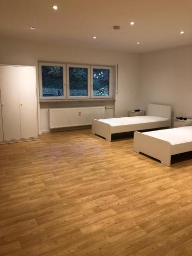 a large room with two beds and wooden floors at Möbilierte 3 Zimmer Wohnung mit großer Wohnküche in Dossenheim
