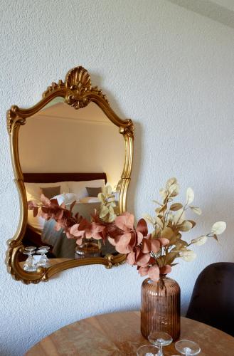 a vase of flowers on a table in front of a mirror at Hotel Schiff am See in Murten