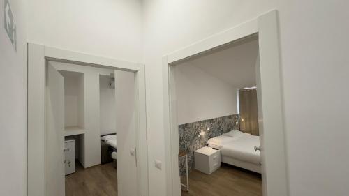 a white room with a bed and a mirror at Le Querce Appartamento Roma in Infernetto