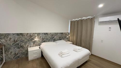 a bedroom with a white bed and a floral wallpaper at Le Querce Appartamento Roma in Infernetto