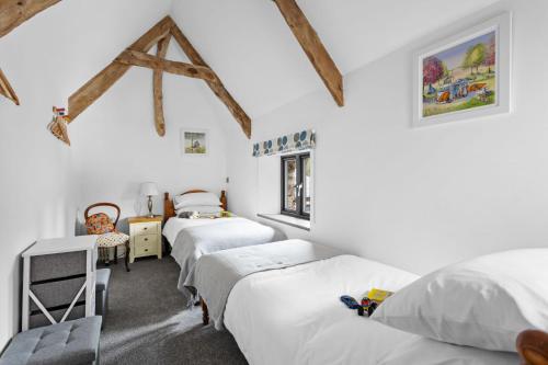 a bedroom with four beds in a room with wooden beams at The Granary, Higher Yalberton Farm in Paignton