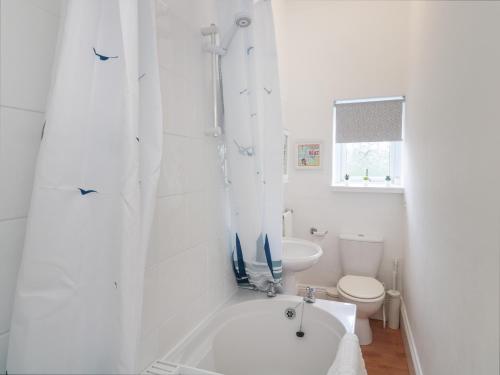 a white bathroom with a tub and a toilet at 14 Birtley Avenue in North Shields