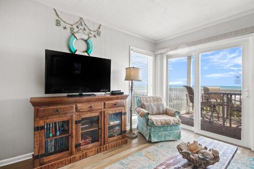 a living room with a flat screen tv and a chair at Ocean Pier #122 in Myrtle Beach
