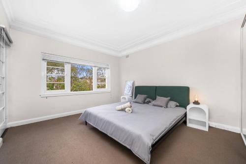 a white bedroom with a bed and a window at Harbour Bridge View 2BR Resort in Sydney