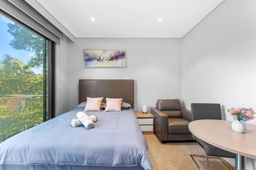 a bedroom with a bed and a chair and a table at Nice and quite studio Roseville in Sydney