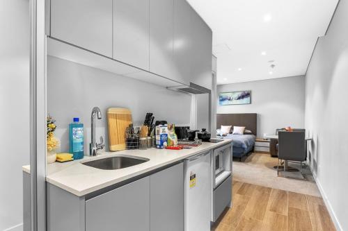a kitchen with a sink and a living room at Studio in heart of Roseville in Sydney