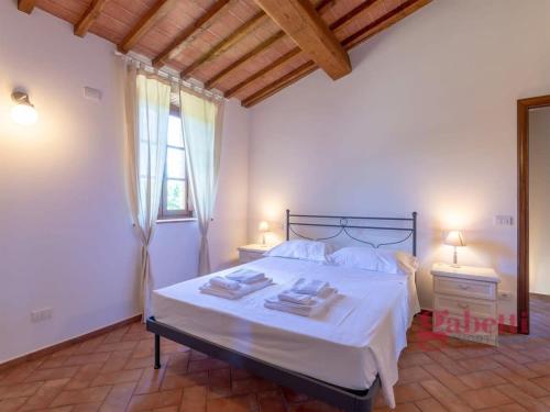 a bedroom with a bed with white sheets and a window at La Loggia - I Borghi Della Selvaccia in Cennina