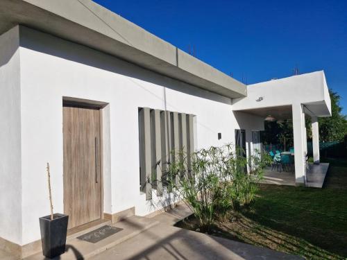 a white house with a wooden door and a yard at Casa COMODA Y MODERNA in San Fernando del Valle de Catamarca