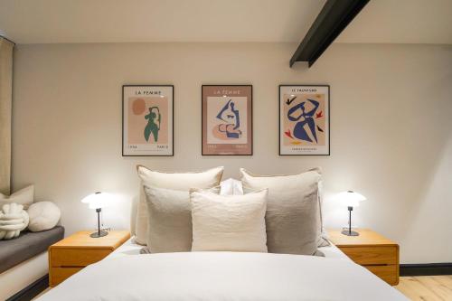 a bedroom with a white bed with three pictures on the wall at Omnia by The Heim Residences in Manchester