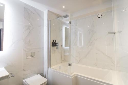 a white bathroom with a shower and a toilet at Omnia by The Heim Residences in Manchester