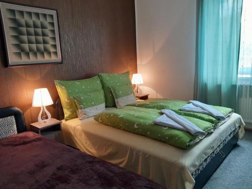 um quarto com uma cama com lençóis e almofadas verdes em Varázsfa Vendégház em Demjén