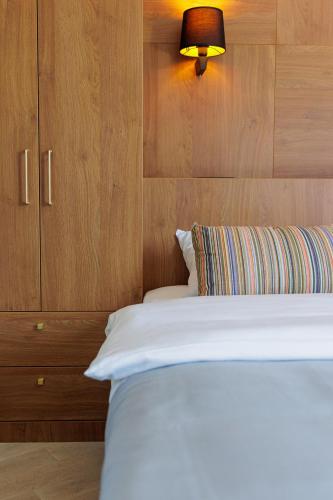 a bedroom with a white bed with a wooden wall at Hotel Kadmo by Aycon in Budva