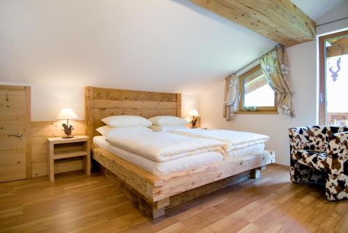 Schlafzimmer mit einem großen Bett mit einem Kopfteil aus Holz in der Unterkunft Das Bäckergut am Haldensee in Haldensee