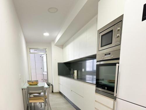 een keuken met een magnetron en een tafel met stoelen bij Piso en el centro de Vigo 2 dormitorios Brasil in Vigo