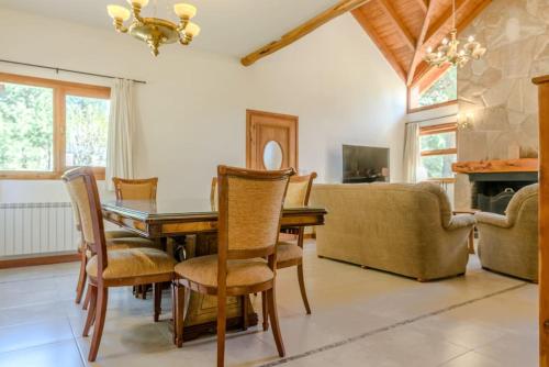 a dining room with a table and chairs and a couch at Casa en Bosque de Pinos in San Carlos de Bariloche