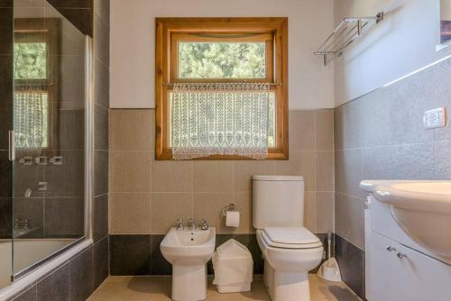 a bathroom with a toilet and a sink and a window at Casa en Bosque de Pinos in San Carlos de Bariloche