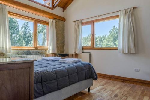 1 dormitorio con 1 cama y 2 ventanas en Casa en Bosque de Pinos en San Carlos de Bariloche