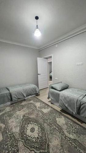1 dormitorio con 2 camas y alfombra en Avocado en Bishkek