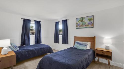 2 Betten in einem Zimmer mit blauer Bettwäsche und blauen Vorhängen in der Unterkunft Sarasota home with Outdoor Oasis in Sarasota