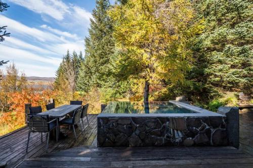 a wooden deck with a table and a swimming pool at Luxury Lakefront villa, infinity hot tub and sauna in Grímsnes og Grafningshreppur