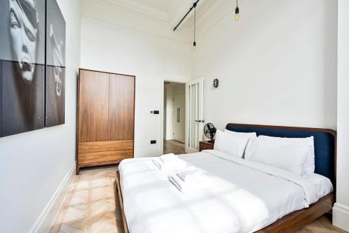una camera con un letto bianco e una porta in legno di GuestReady - Luxury haven in Palmers Green a Palmers Green
