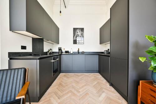 a kitchen with gray cabinets and a wooden floor at GuestReady - Luxury haven in Palmers Green in Palmers Green