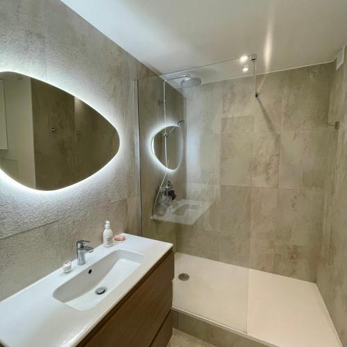ein Bad mit einem Waschbecken und einer Dusche mit einem Spiegel in der Unterkunft Shiny apartment - Direct line to Olympic Village in Clichy