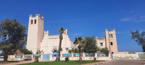 a building with two towers with palm trees in front at Maison Xanadu in Sidi Ifni