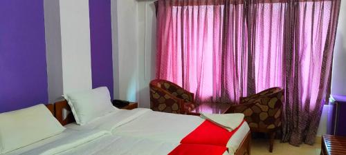 a bedroom with a bed and a window with pink curtains at Manhattan in Chennai