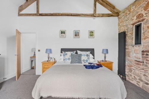 a bedroom with a bed and a brick wall at The Linhay, Higher Yalberton Farm in Paignton