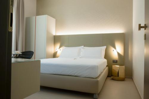 una camera da letto con letto, lenzuola e cuscini bianchi di B&B il Divino a Napoli