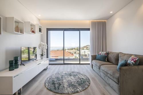 a living room with a couch and a large window at Contemporary Residence B by Homie in Funchal