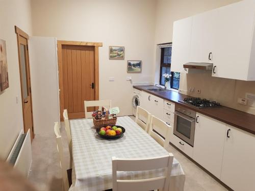 a kitchen with a table with a bowl of fruit on it at Hollymount Cottage in Cranley