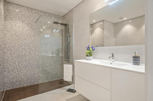 een witte badkamer met een wastafel en een douche bij Contemporary Residence C by Madeira Sun Travel in Funchal